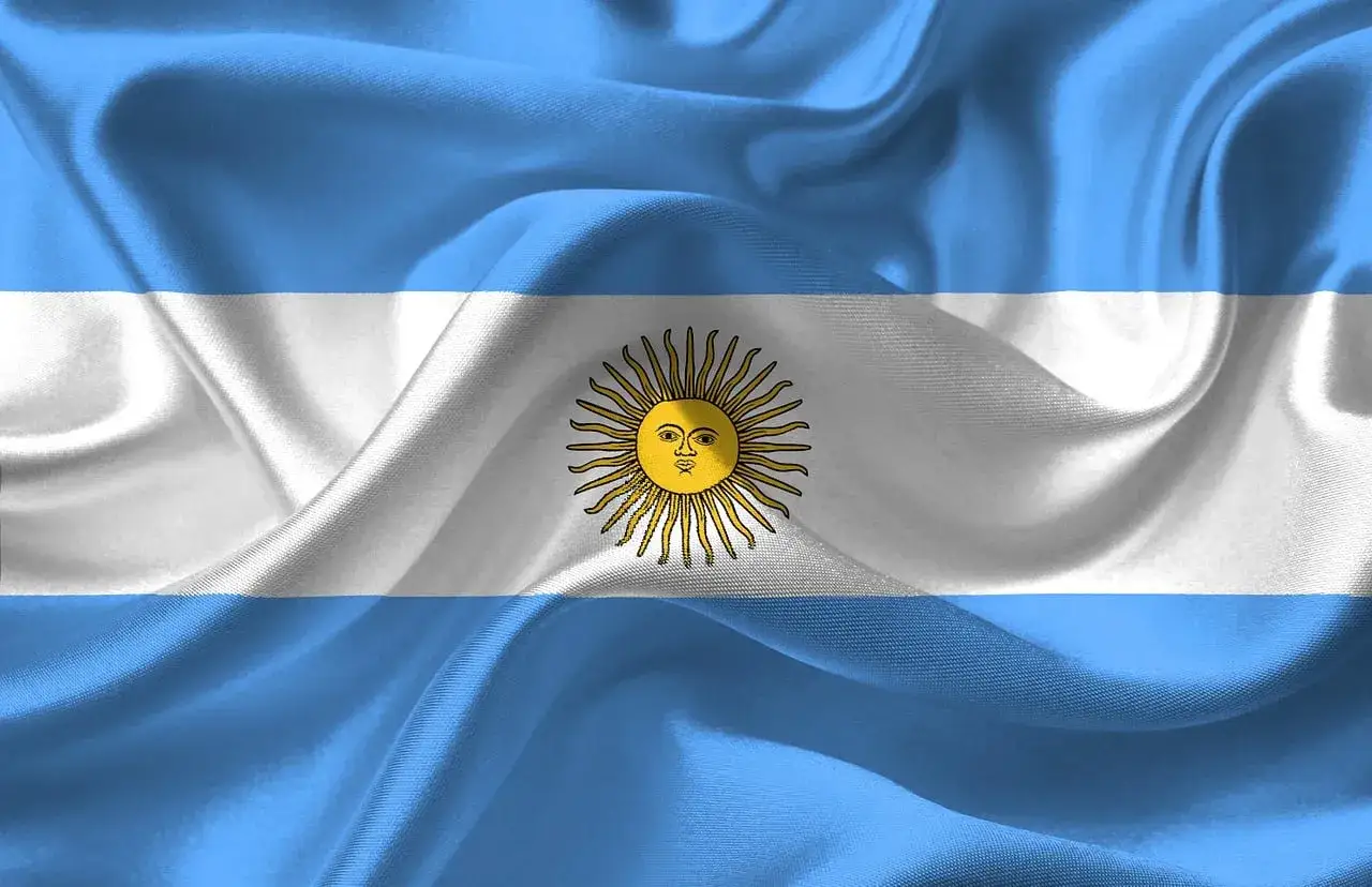 Flaga Argentyny: trzy poziome pasy – dwa jasnoniebieskie na górze i dole, biały pośrodku, a w centrum złote Słońce Majowe.