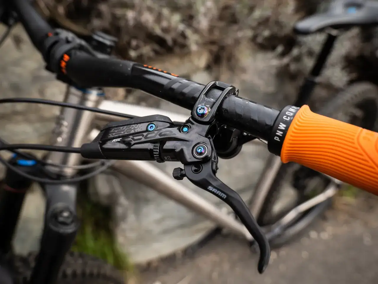 Close-up of a SRAM brake lever with RSC branding, attached to a mountain bike handlebar with an orange grip.