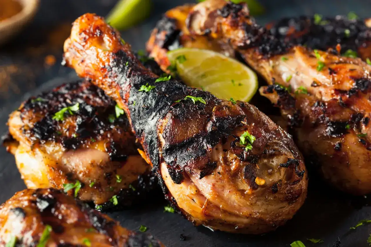Grillad piri piri kyckling med lime och persilja. Saftiga kycklingklubbor med perfekt grillad yta, redo att avnjutas.