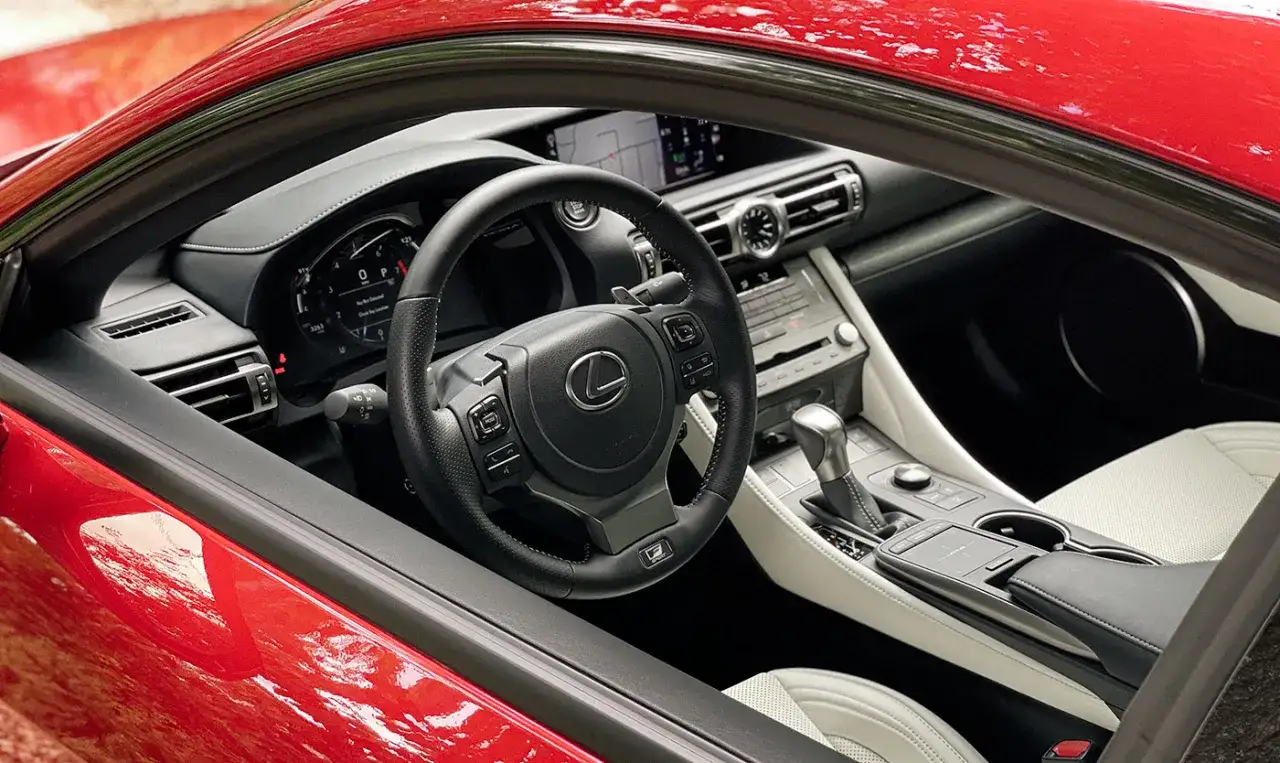Wnętrze czerwonego Lexusa RC 350 z czarną kierownicą i jasnymi siedzeniami.