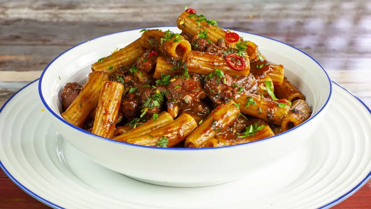 Rigatoni conditi con un ricco rag&ugrave; di polpo, guarniti con prezzemolo fresco e peperoncino.