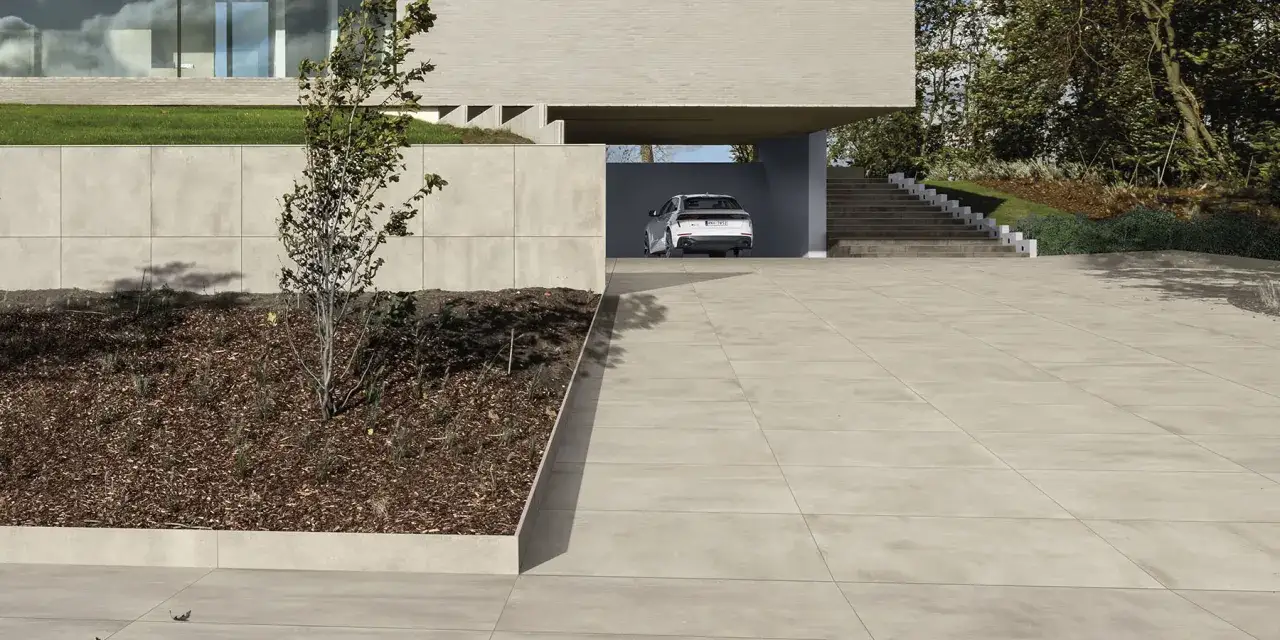 Vialli con gres carrabile moderno, un'auto bianca parcheggiata sotto un tetto spiovente, circondata da un giardino curato e una casa minimalista.