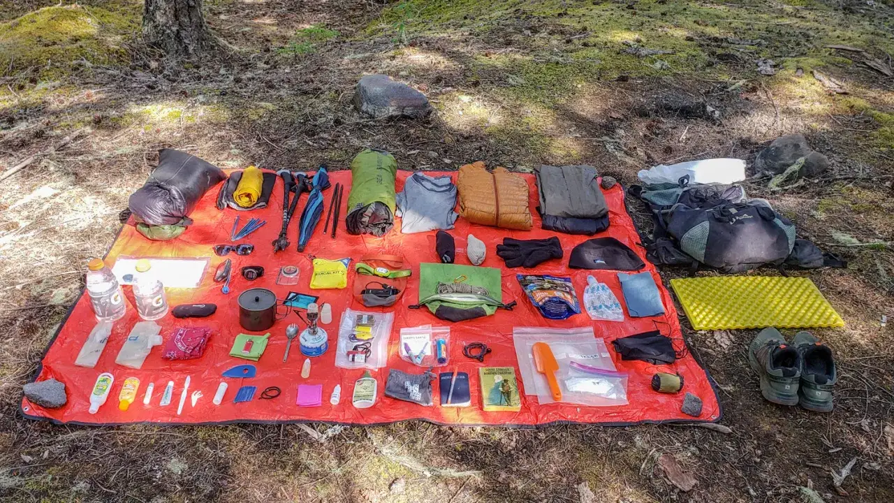 Wander-Essentials ausgebreitet: Rucksack, Kleidung, Kocher, Erste-Hilfe-Set, Schuhe und mehr f&uuml;r ein Abenteuer.