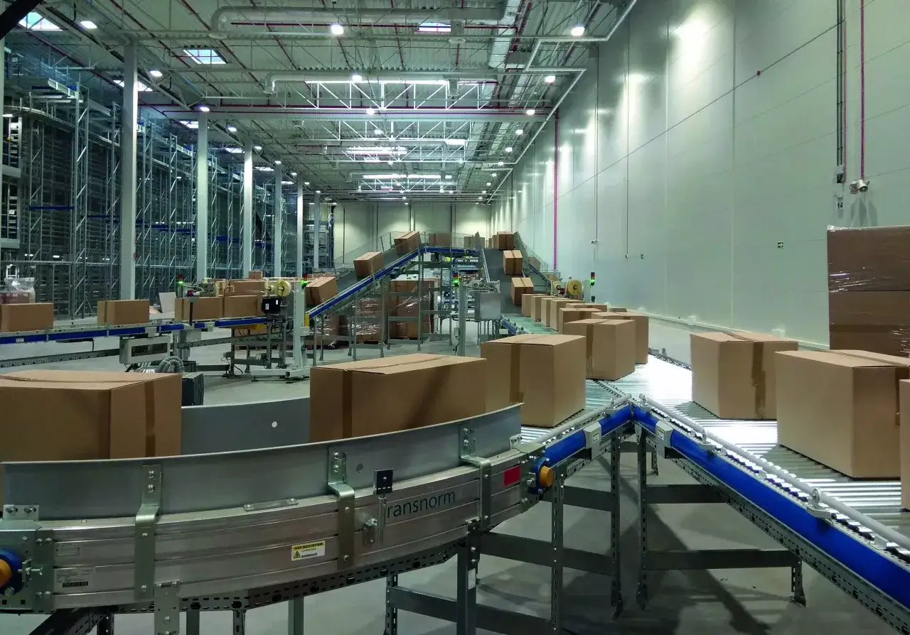 Nowoczesny magazyn e commerce z taśmociągami i kartonami. Automatyzacja procesów logistycznych w centrum dystrybucyjnym.
