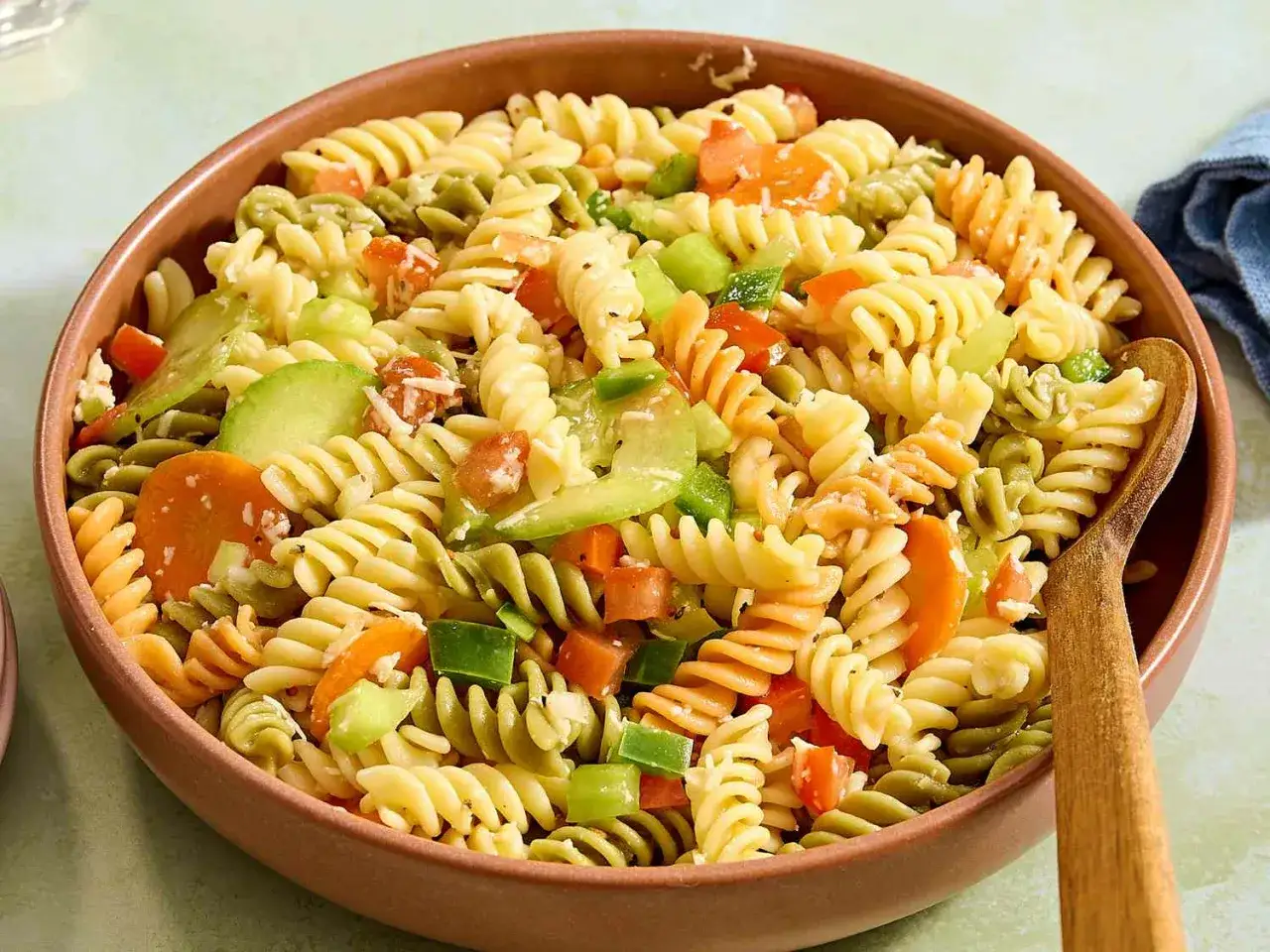 Bunter Nudelsalat ohne Mayonnaise mit Spiralnudeln, Karotten, Paprika und Gurke in einer Schüssel.