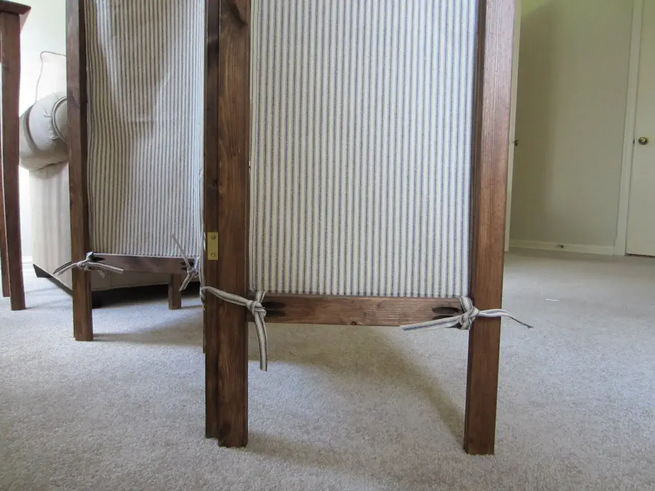 Deux panneaux de paravent en bois avec tissu à rayures bleues et blanches, attachés par des liens. Idéal pour fabriquer un paravent DIY.
