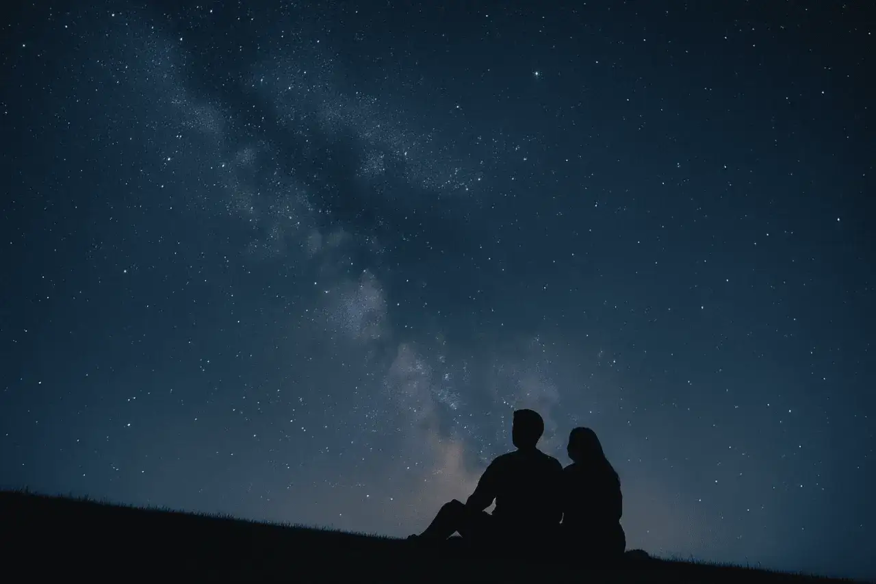 Un couple en silhouette admire la Voie lactée, une parfaite idée de rendez-vous romantique sous les étoiles.