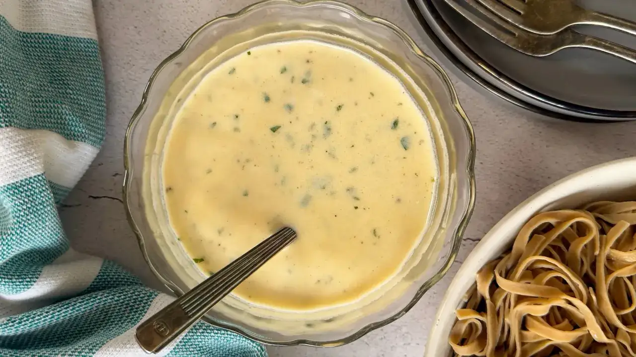 Cremige, low carb Béchamel mit Kräutern in einer Glasschüssel, bereit, über Pasta gegossen zu werden.