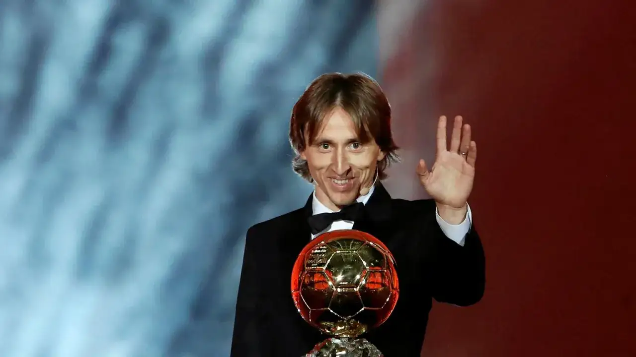 Luka Modrić z Złotą Piłką, triumfalnie wznosi rękę, świętując swoje zasłużone zwycięstwo.