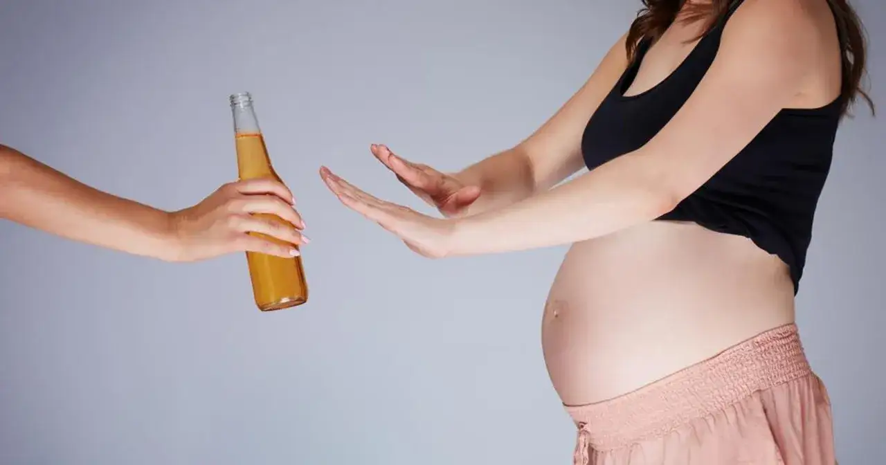 Ciężarna kobieta odrzuca butelkę piwa bezalkoholowego. Zdrowie dziecka jest najważniejsze.