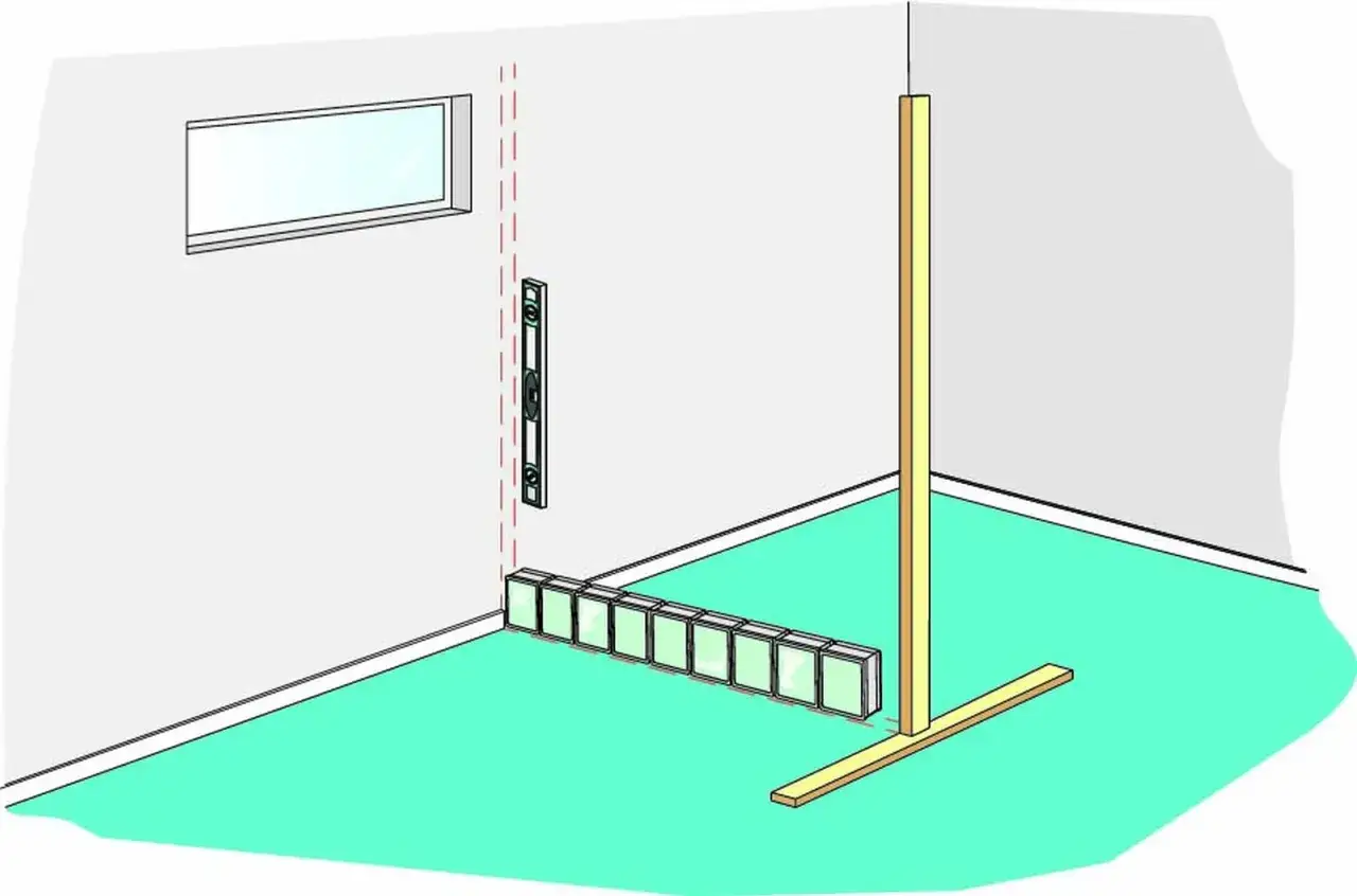 Byggnation av en vägg med mura glasblock. En vattenpass visar att det är rakt.