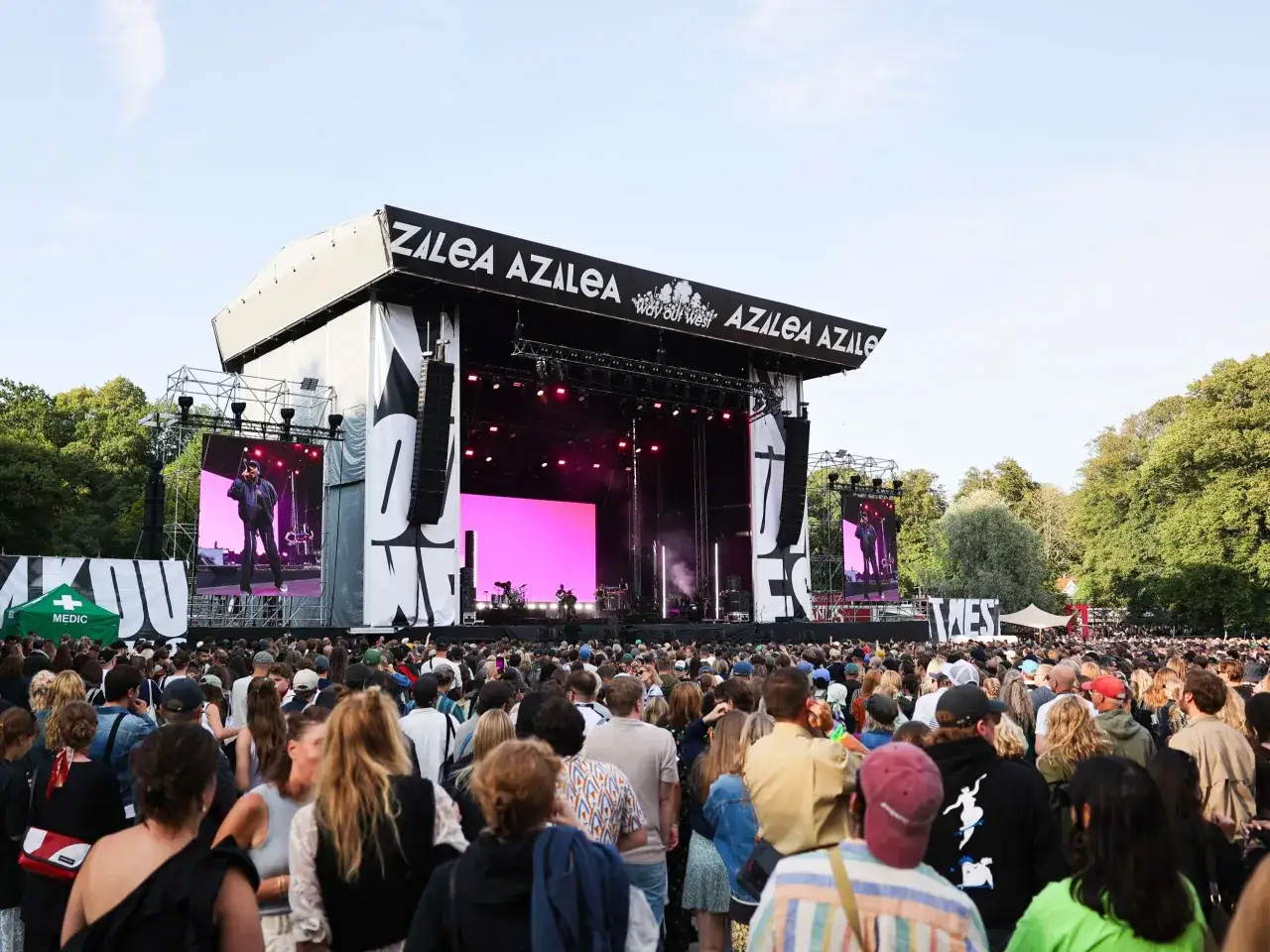 Stor publik vid Way Out West-festivalen i Göteborg. En artist uppträder på scenen med en stor rosa bakgrund.
