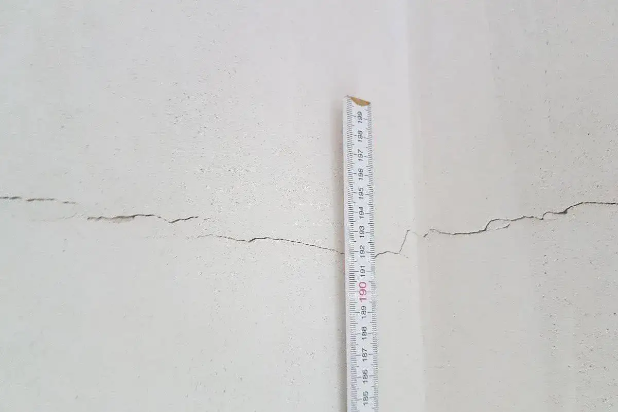 Riss im Putz der Fensterlaibung, gemessen mit einem Maßstab. Vorbereitung für das Fensterlaibung verputzen.