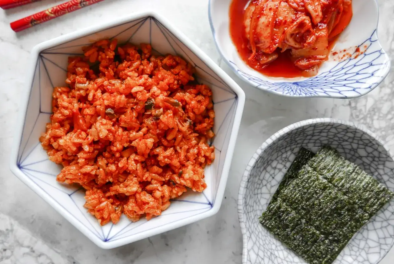 Pikantny ryż z dodatkiem kimchi, obok miseczka z kiszoną kapustą i nori. Pyszne danie, które pokazuje, co to jest kimchi.
