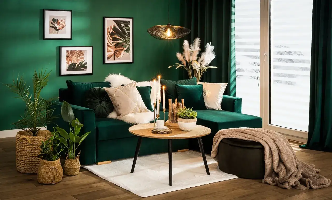 Elegancki salon w odcieniach butelkowej zieleni i beżu. Miękka kanapa, stylowe dodatki i rośliny tworzą przytulną atmosferę.