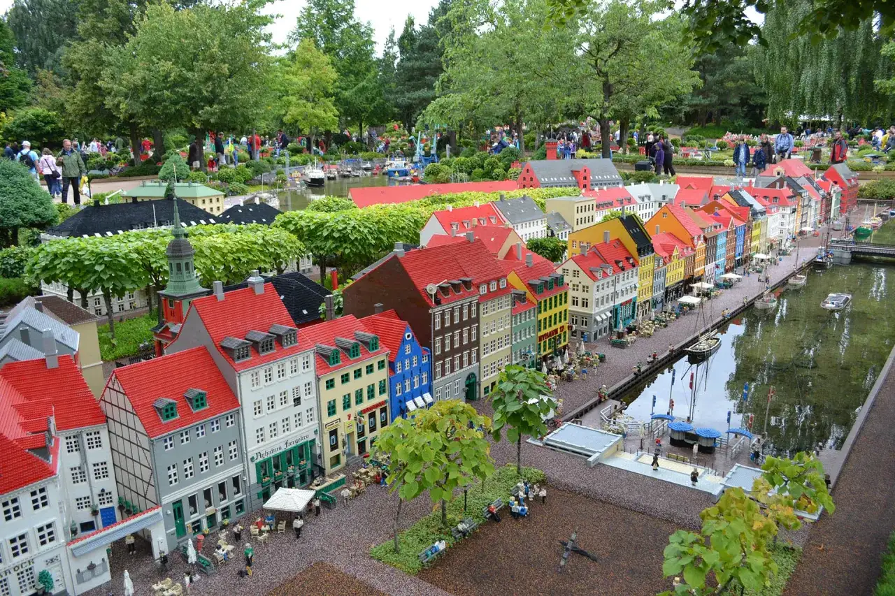 Kolorowe kamienice nad kanałem, z czego słynie Kopenhaga. Miniaturowa zabudowa, łodzie i spacerujący ludzie.