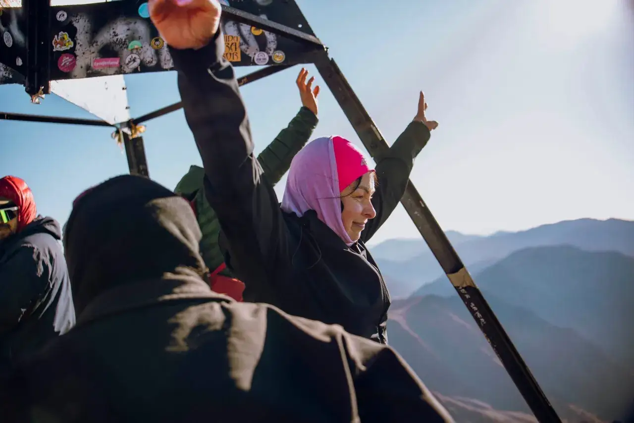 Radość na szczycie Jebel Toubkal w Maroku. Kobieta w różowej chuście świętuje z podniesionymi rękami.