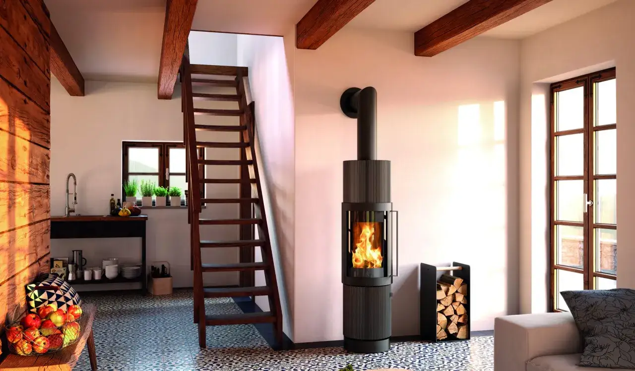 Un poêle moderne et chaleureux est installé sous un escalier en bois, créant un coin cosy.