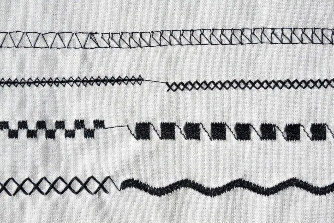 Various decorative sewing seams on white fabric, showcasing zigzag, diamond, and wave patterns.