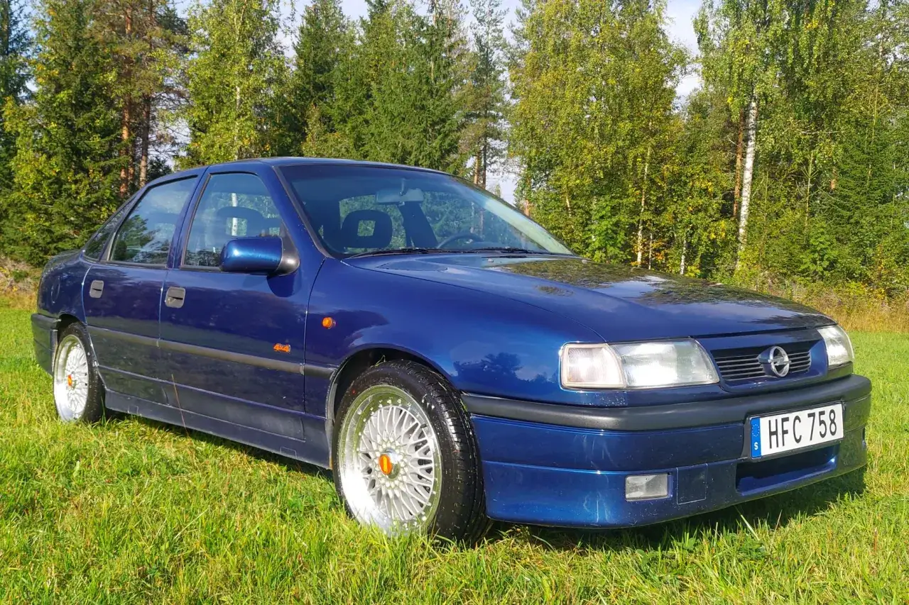 Bl&aring; Opel Vectra p&aring; gr&auml;s, med skog i bakgrunden. Kanske en bil som beh&ouml;ver lite k&auml;rlek f&ouml;r att undvika opel vectra vanliga fel.