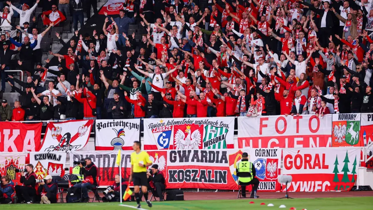 Tłum kibiców z flagami Polski, transparenty z nazwami drużyn i hasłami, tworzą atmosferę sportowych **rankingów i ligi**.