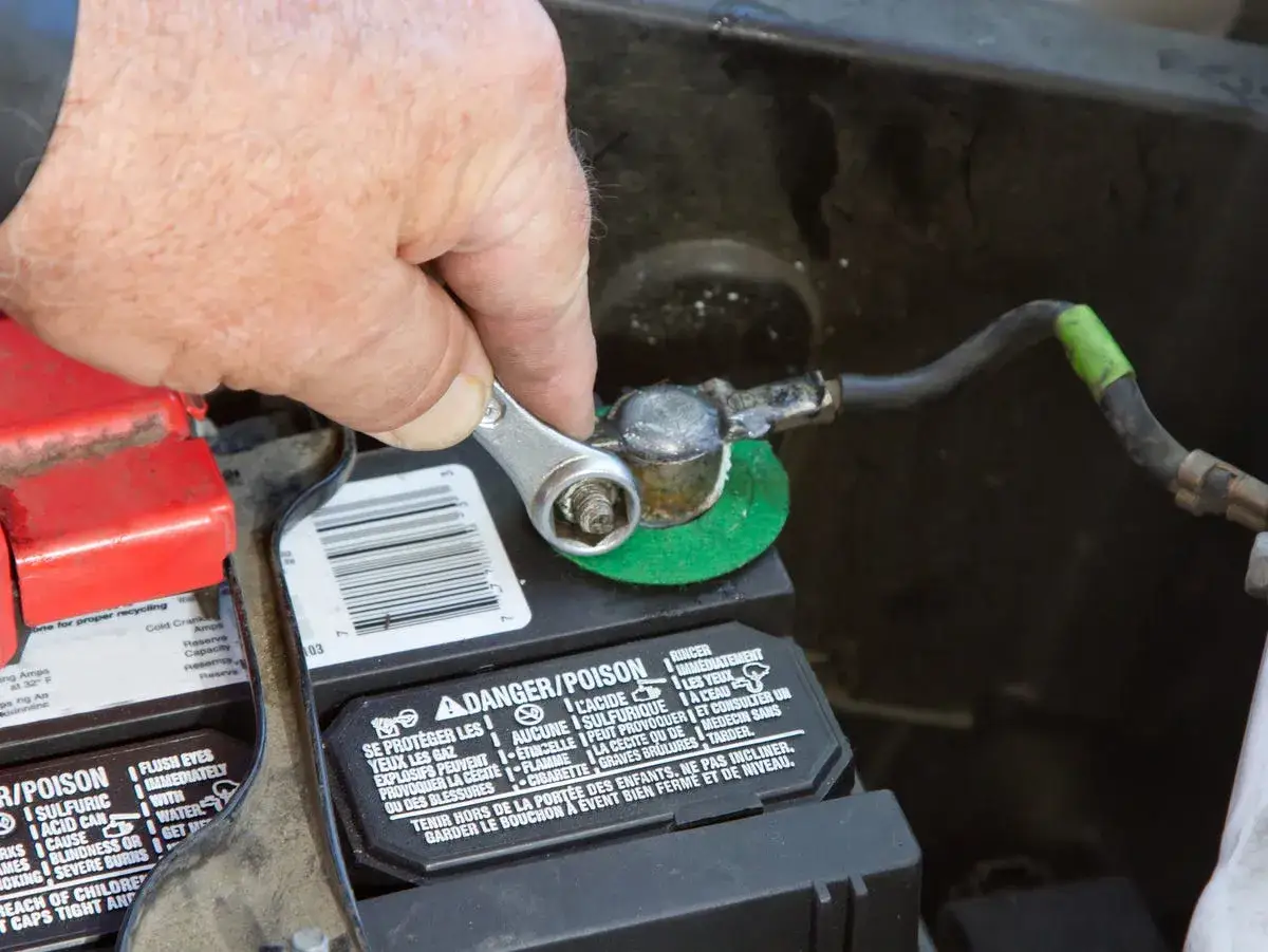 Mano con llave inglesa para desconectar la batería del coche.