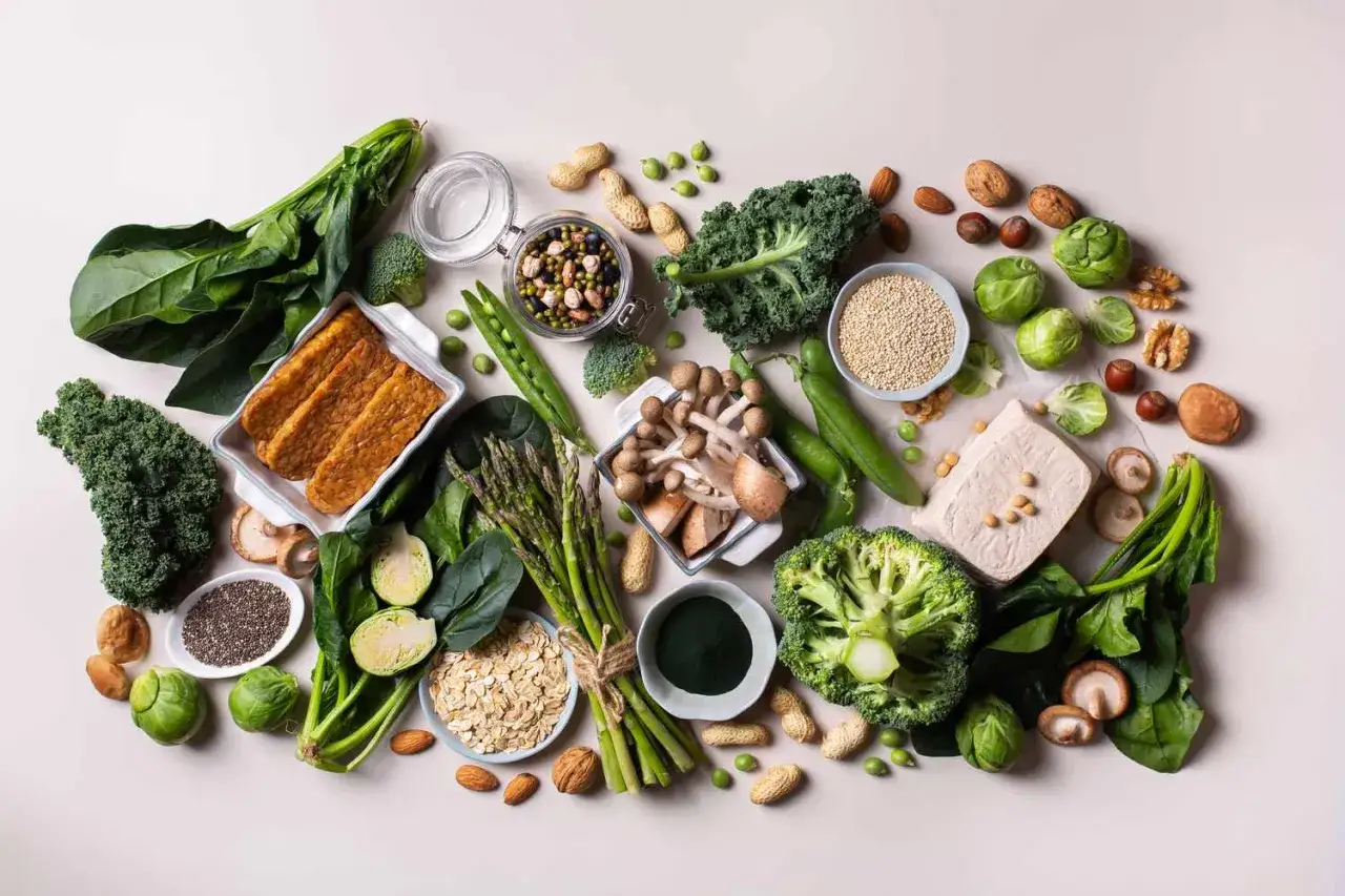 Vielfalt an pflanzlichen Lebensmitteln: Tempeh, Tofu, Linsen, Quinoa, Nüsse, Brokkoli, Spinat, Grünkohl, Spargel, Erbsen, Pilze, Haferflocken. Ideal zur Berechnung, wie viel Protein pro kg.