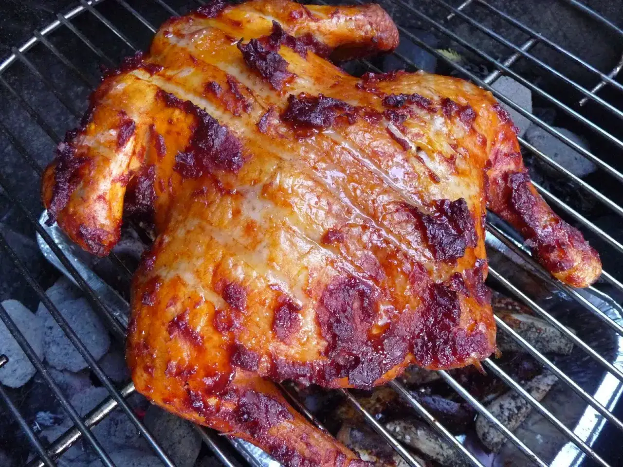 Un poulet entier, la peau dorée et caramélisée, cuit sur un barbecue. Un délice de fumoir poulet !