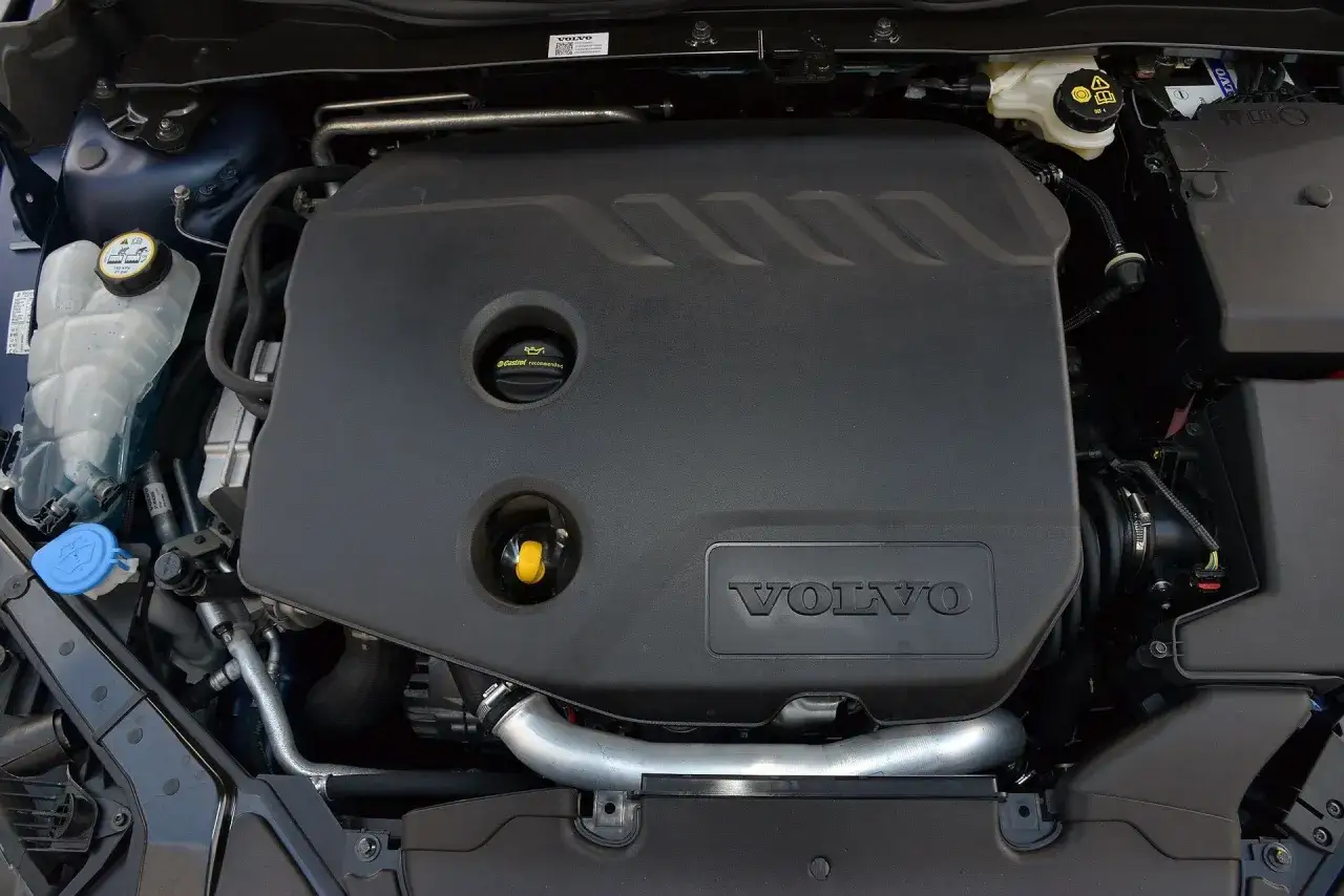 Silnik Volvo V40 D2 z widocznym logo Volvo na czarnej osłonie. Widać zbiornik płynu chłodniczego i inne elementy komory silnika.