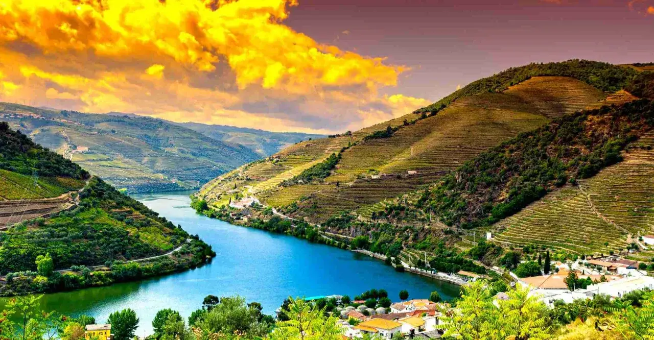 Malerische Flusslandschaft im **Portugal Norden** mit terrassierten Weinbergen, die sich an steile Hänge schmiegen. Ein blauer Fluss schlängelt sich durch das Tal.