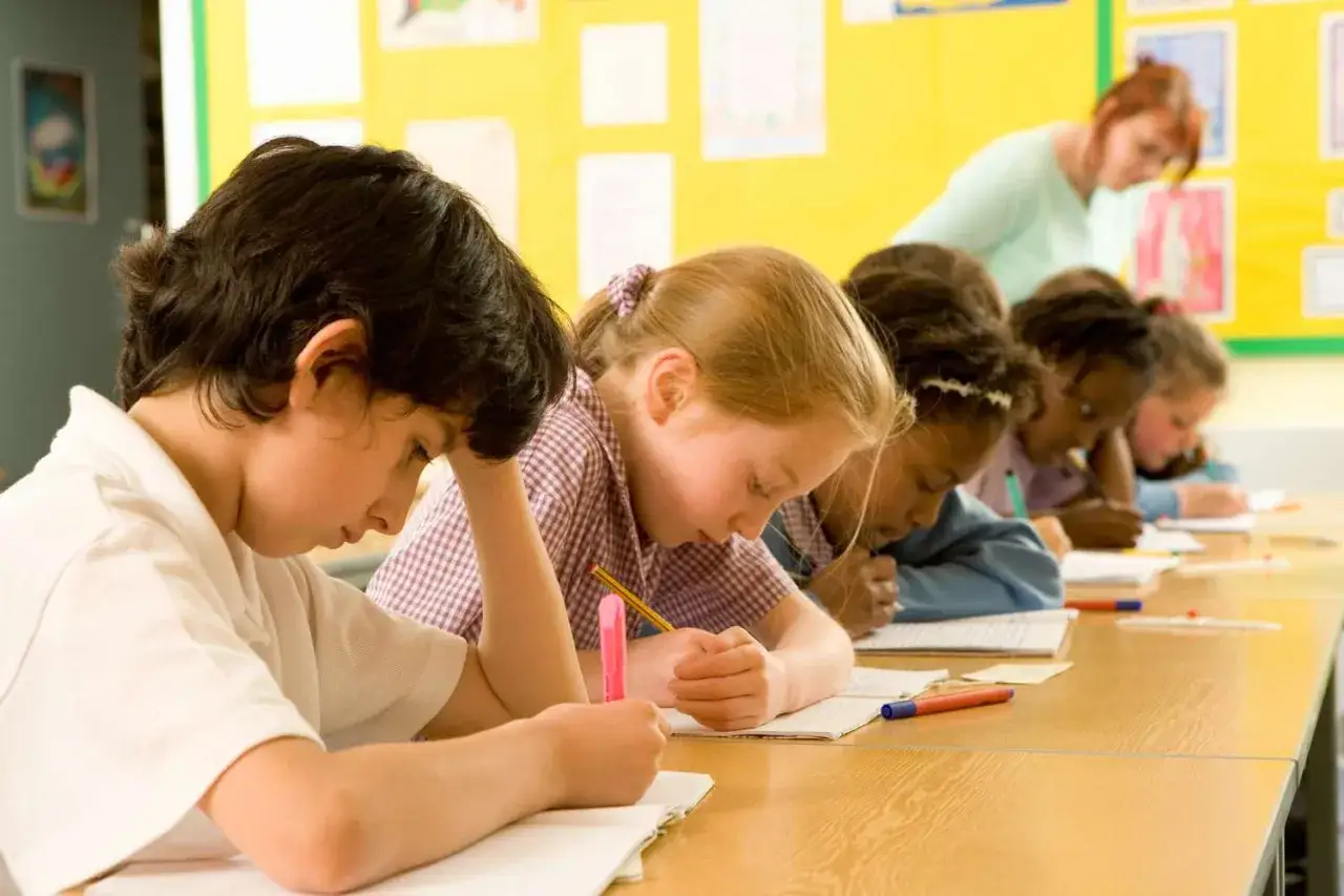 Kinder konzentriert bei **ritualen für ruhe im unterricht**. Eine Lehrerin beobachtet.