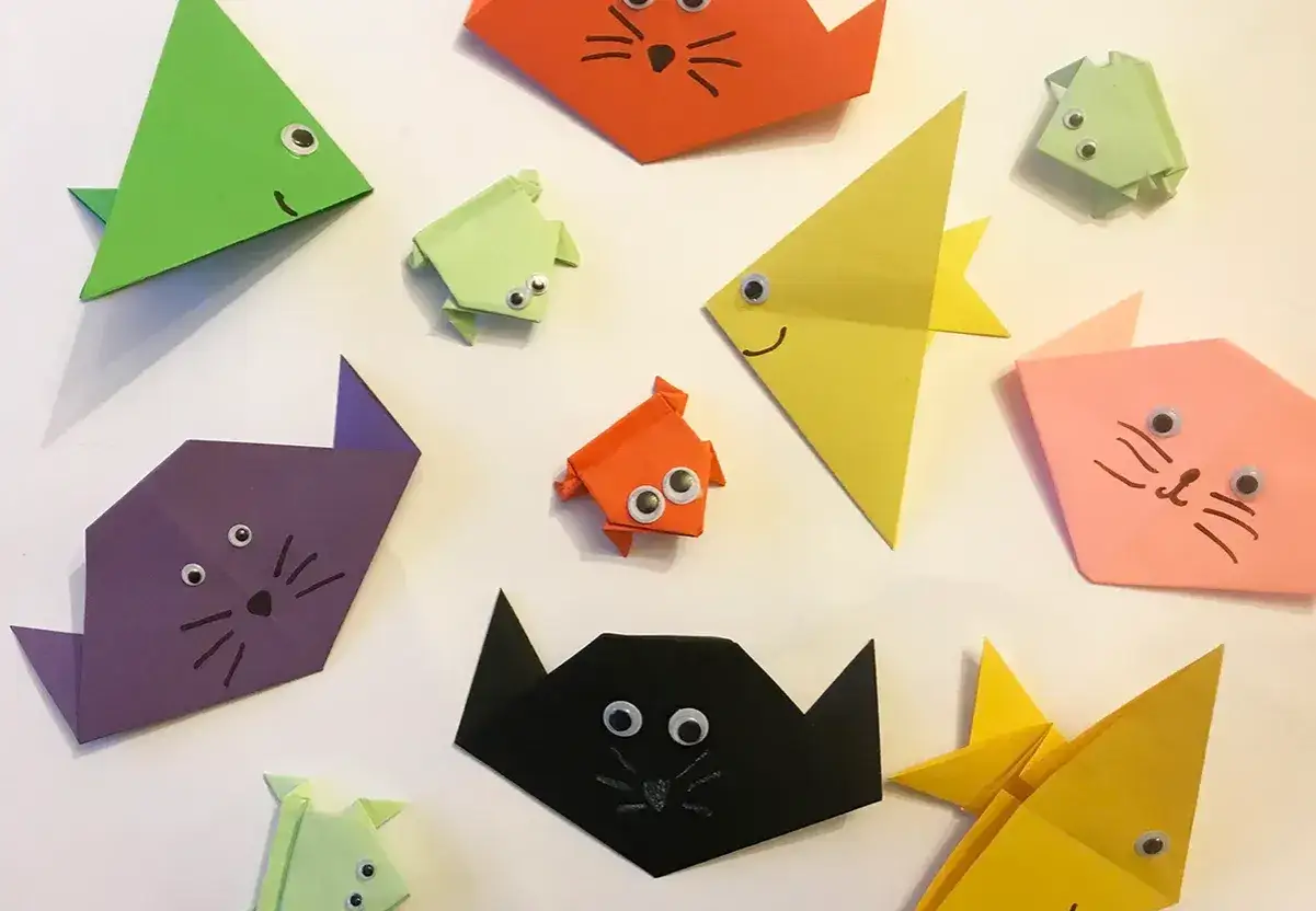 Bunte Origami-Tiere, wie Katzen und Fische, mit aufgemalten Gesichtern und Knopfaugen. Ein fröhlicher Haufen Origami Kinder.