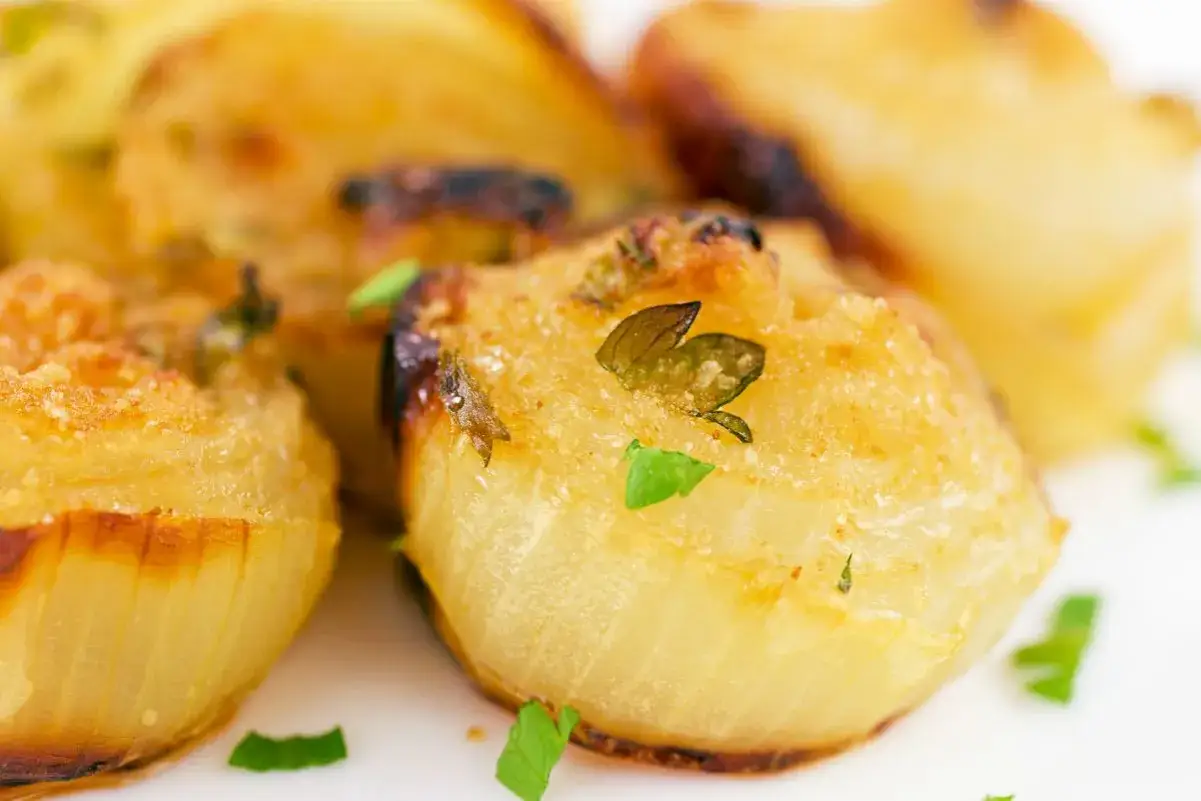 Cipolle al forno dorate e profumate, guarnite con erbe aromatiche fresche. Un contorno saporito e invitante.