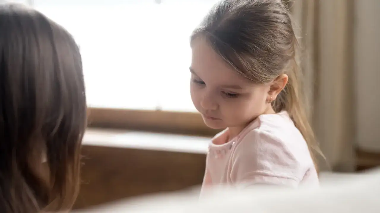 Bambina timida ascolta attentamente, forse parte di esercizi per mutismo selettivo.