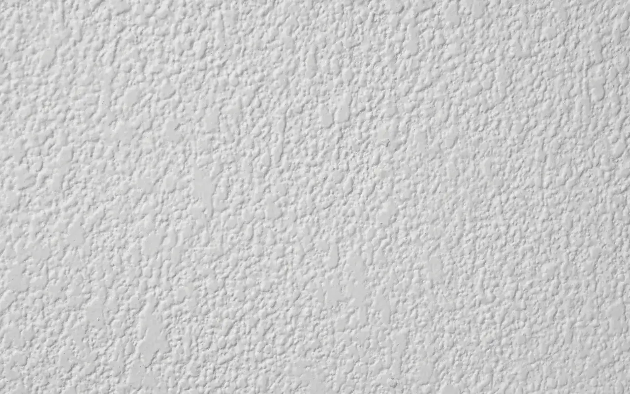 Textura de pintura gotele en la pared, con un acabado rugoso y uniforme que crea un patr&oacute;n de peque&ntilde;as gotas.