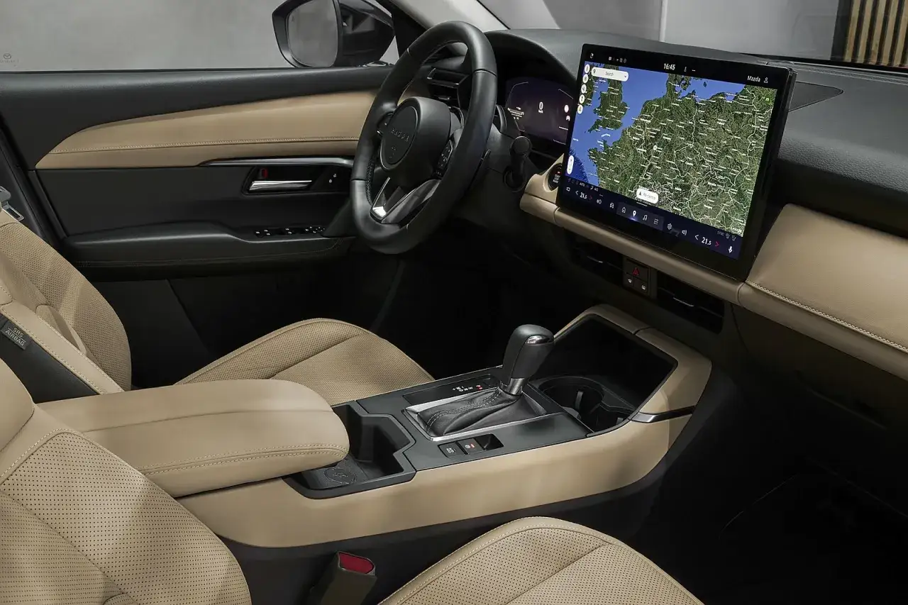 Wnętrze Mazda CX-5 2026 z beżową tapicerką i dużym ekranem nawigacji.