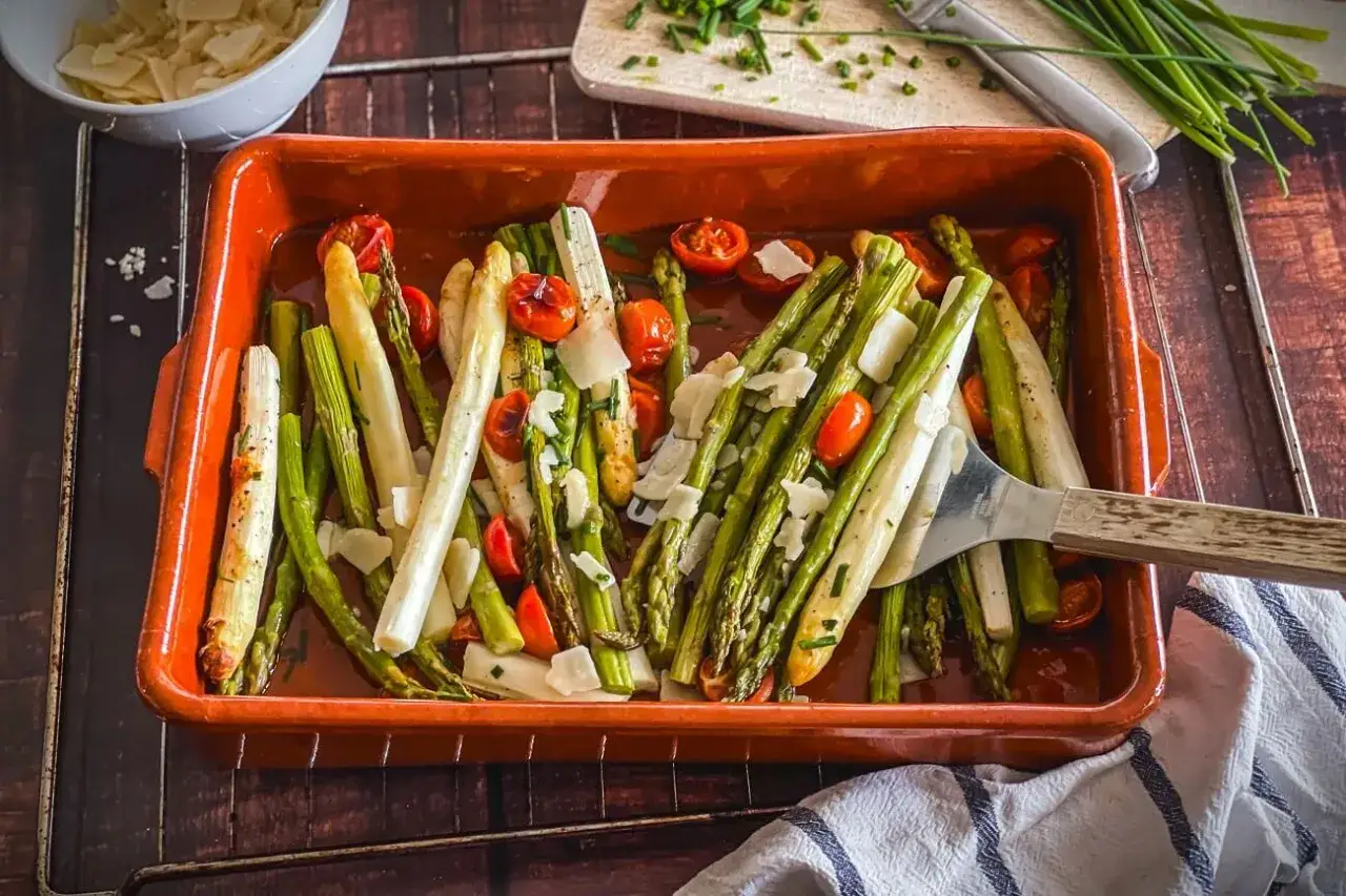 Frischer Spargel, gr&uuml;n und wei&szlig;, mit Kirschtomaten und Parmesan in einer Auflaufform. Ein k&ouml;stliches Gericht, das an Spargel in Alufolie erinnert.