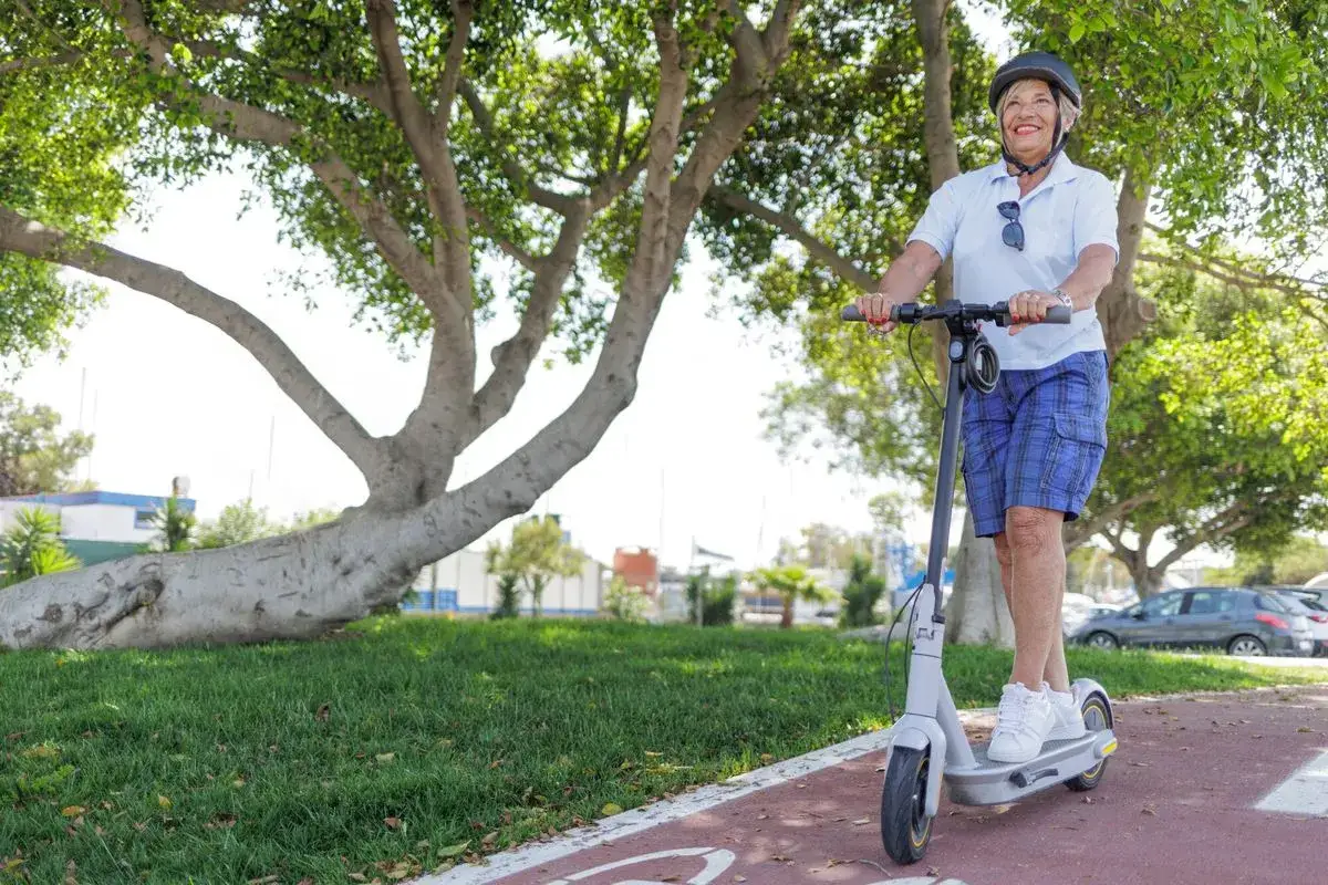 Une femme souriante profite de son trajet en trottinette électrique, une application de mobilité urbaine à portée de main.