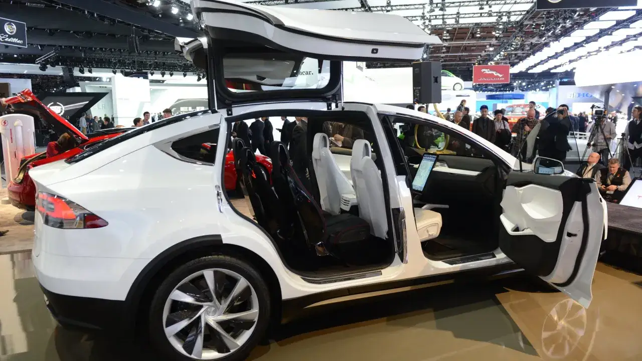 Biały Tesla X z otwartymi drzwiami i maską, prezentujący wnętrze. Cena tego modelu jest atrakcyjna.