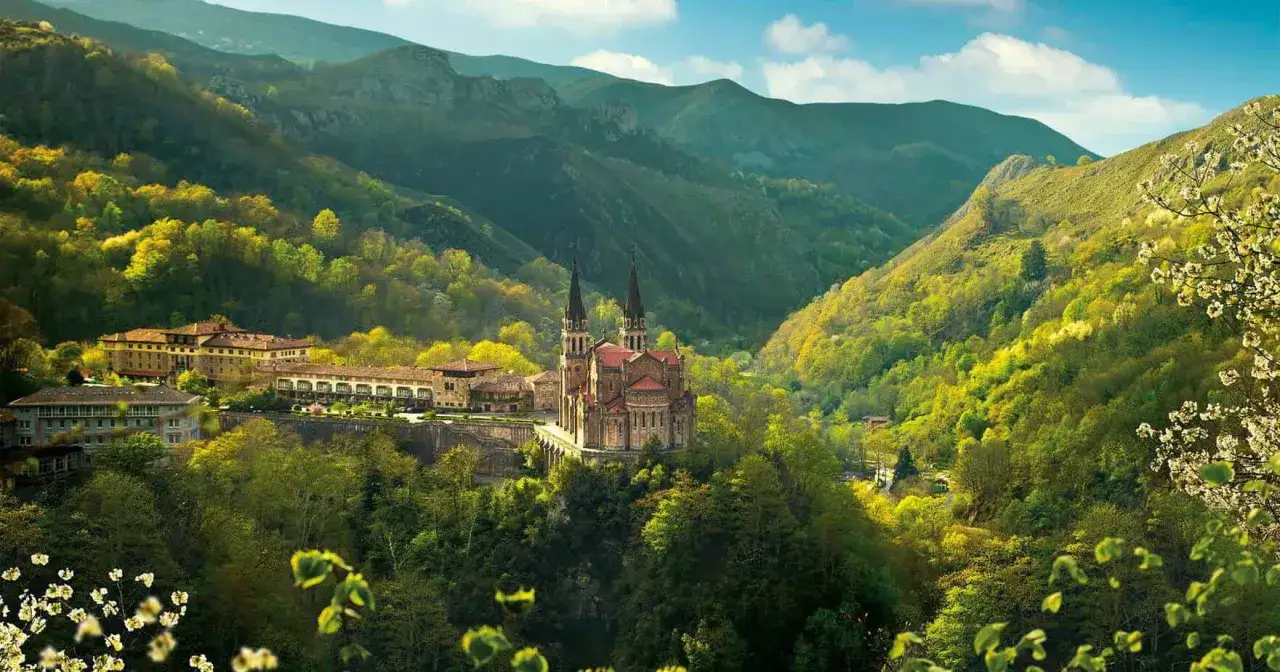 Basílica de Covadonga, un lugar imprescindible que ver en Cangas de Onís, rodeada de montañas verdes y frondosos bosques.