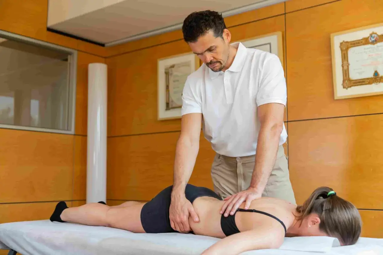 Massaggiatore esperto lavora sulla schiena di una donna per ottenere un profondo rilassamento muscolare.