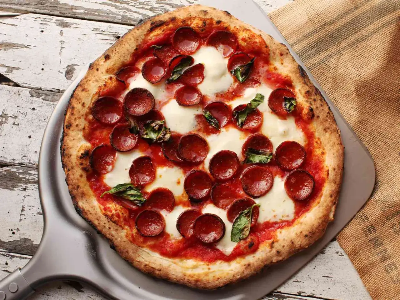 En perfekt napolitansk pizza med pepperoni och basilika, redo att serveras.