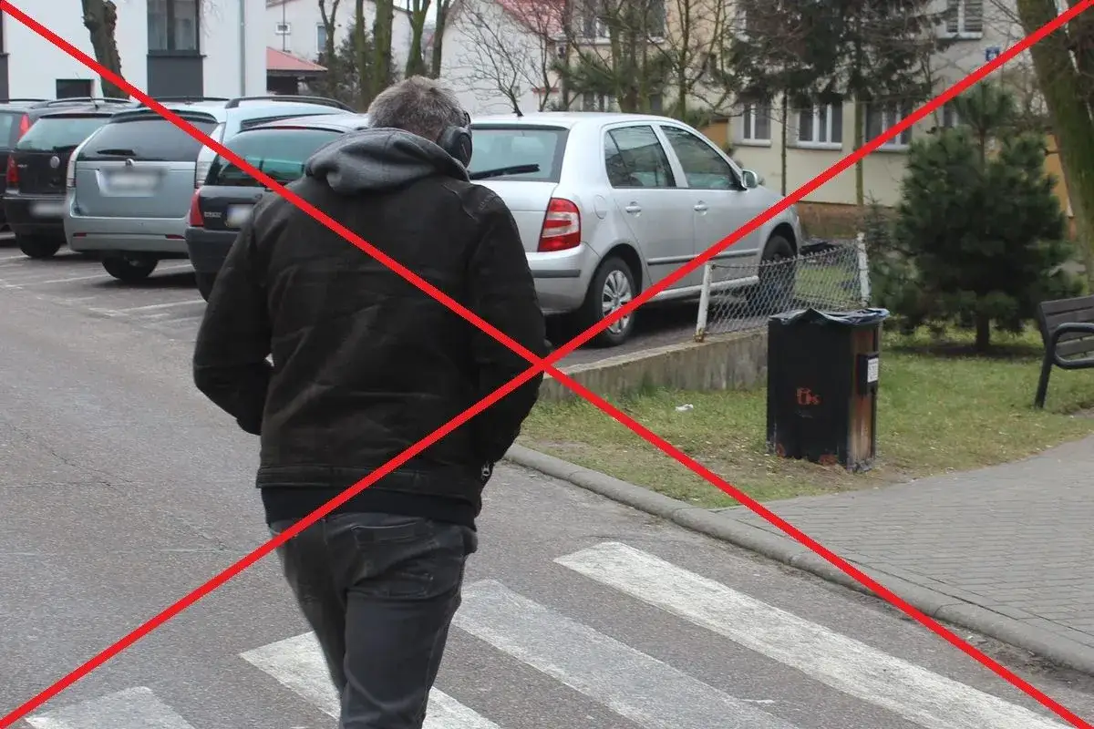 Mężczyzna w słuchawkach przechodzi przez przejście dla pieszych.