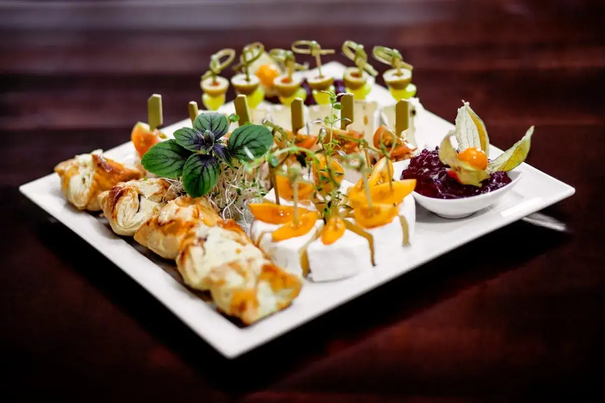 Efektowna kolacja dla znajomych: ser brie, pieczone ciastka, pomidorki koktajlowe i sos żurawinowy.