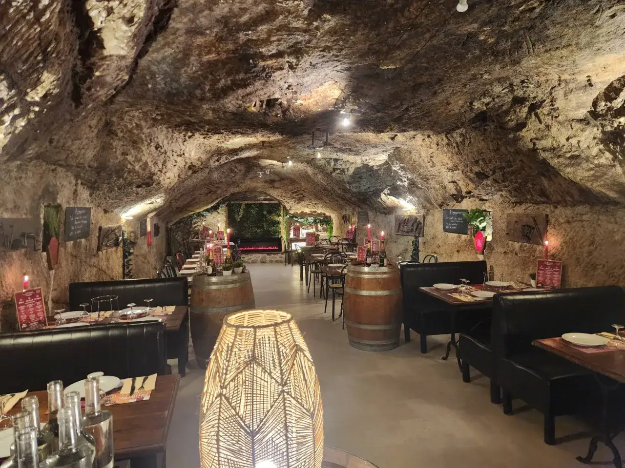 Ambiance troglodyte pour une exp&eacute;rience unique de saumur cuisine. Tables dress&eacute;es, bougies allum&eacute;es, f&ucirc;ts de vin et lampes en rotin cr&eacute;ent un d&eacute;cor chaleureux.