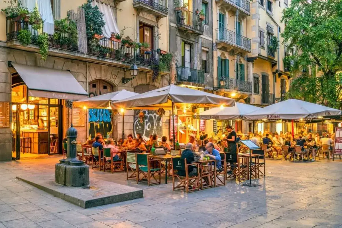 Gente disfrutando de tapas y bebidas en una terraza animada en el barrio de el Born, Barcelona.