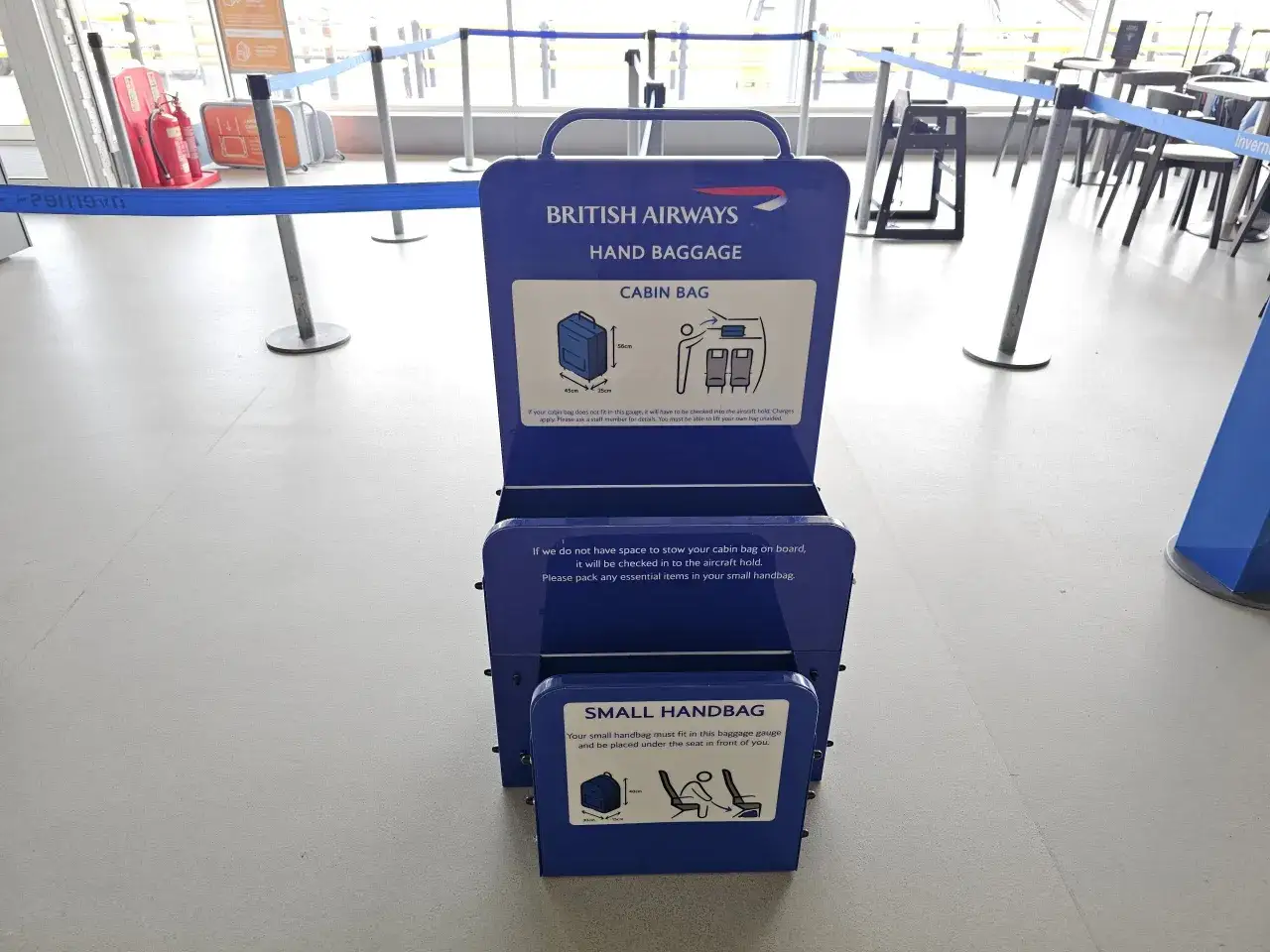Niebieska miarka bagażu podręcznego British Airways na lotnisku. Sprawdź, czy Twój bagaż podręczny zmieści się w wyznaczonych wymiarach.