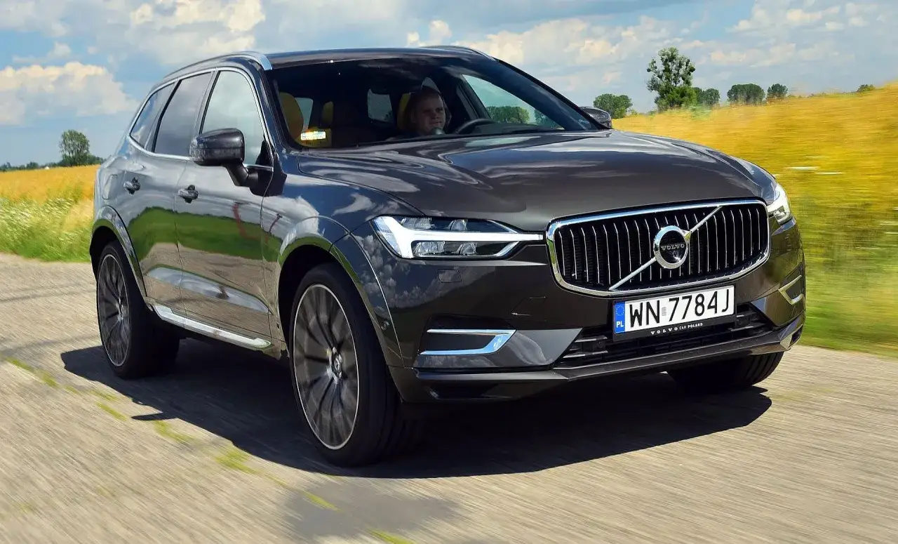 Ciemnoszary Volvo XC60 jedzie po drodze, a za nim rozciąga się pole. Kierowca zastanawia się, ile spala Volvo XC60.