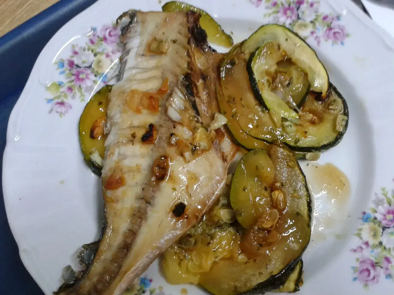 Pescado al horno con rodajas de calabac&iacute;n al horno, todo ba&ntilde;ado en una salsa dorada y arom&aacute;tica.