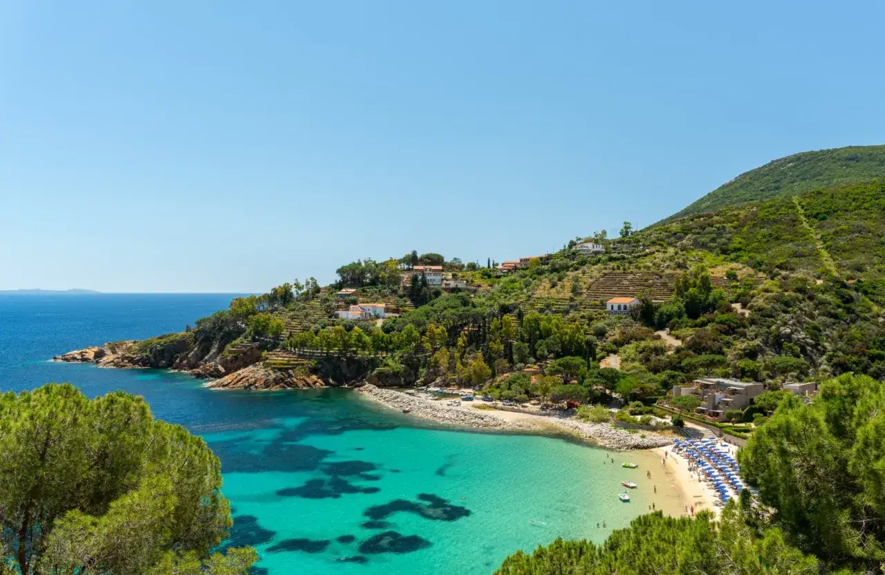 Baia incantevole in una località mare toscana, con acque cristalline, spiaggia attrezzata e ville immerse nel verde collinare.